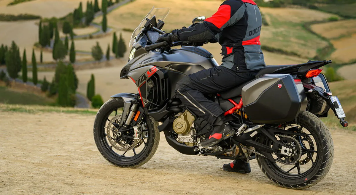 Une moto Ducati Multistrada V4 S Grand Tour 1160 devant une vallée avec quelques arbres.
