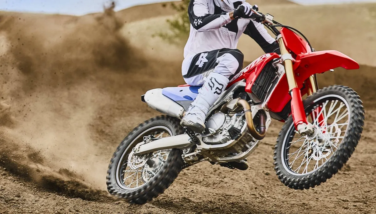 une moto Honda CRF 450 R 2027 rouge et bleu sur un terrain de cross