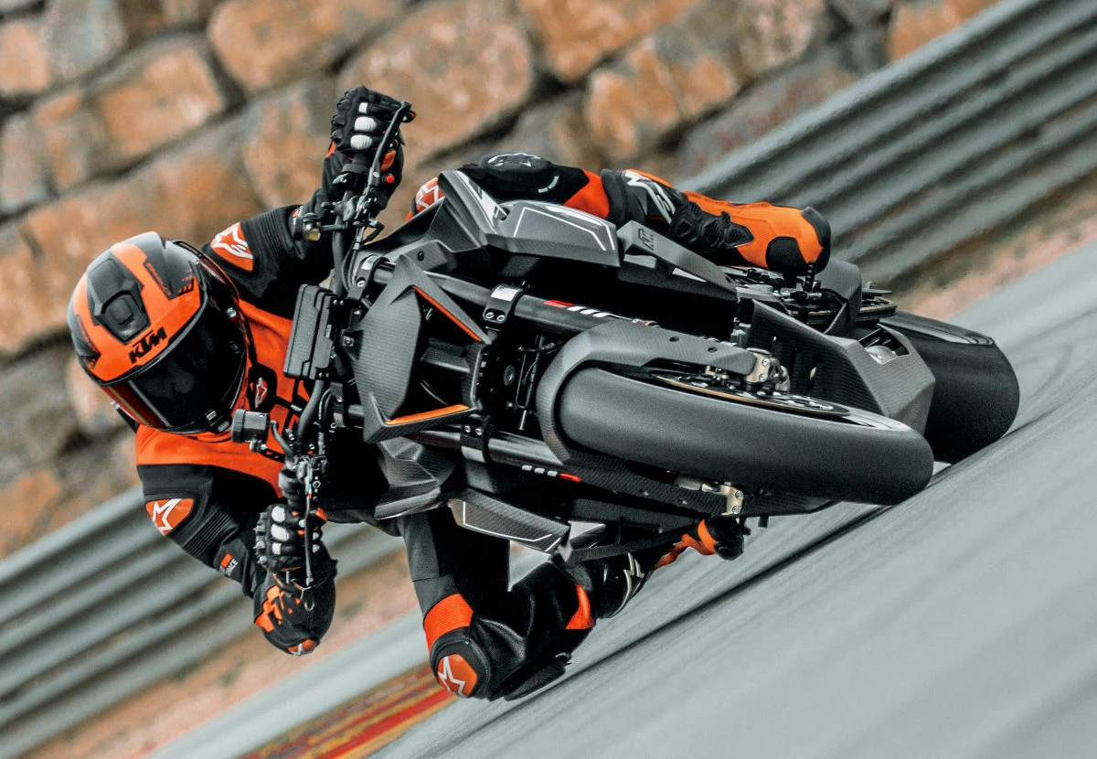 Une moto KTM Superduke 1390 RR Track penché sur circuit, un pilote avec une combinaison en cuir et un casque orange