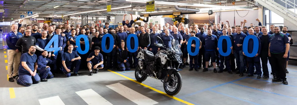 Des ouvriers de BMW tenant des chiffres à l'intérieur d'une usine et une moto BMW R 1300 GS Adventure grise et noire