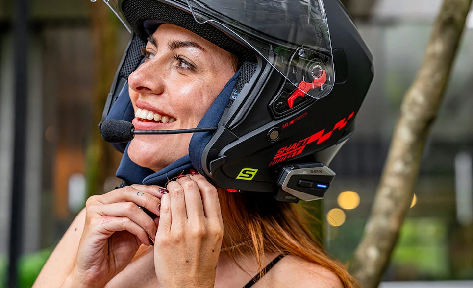 Un visage de femme, des mains de femme accrochant la jugulaire d'un casque jet et un intercom Sena Vortex