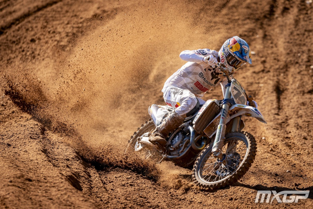 Kay De Wolf, in her white outfit and riding her white Husqvarna, kicking up dirt as she takes a turn
