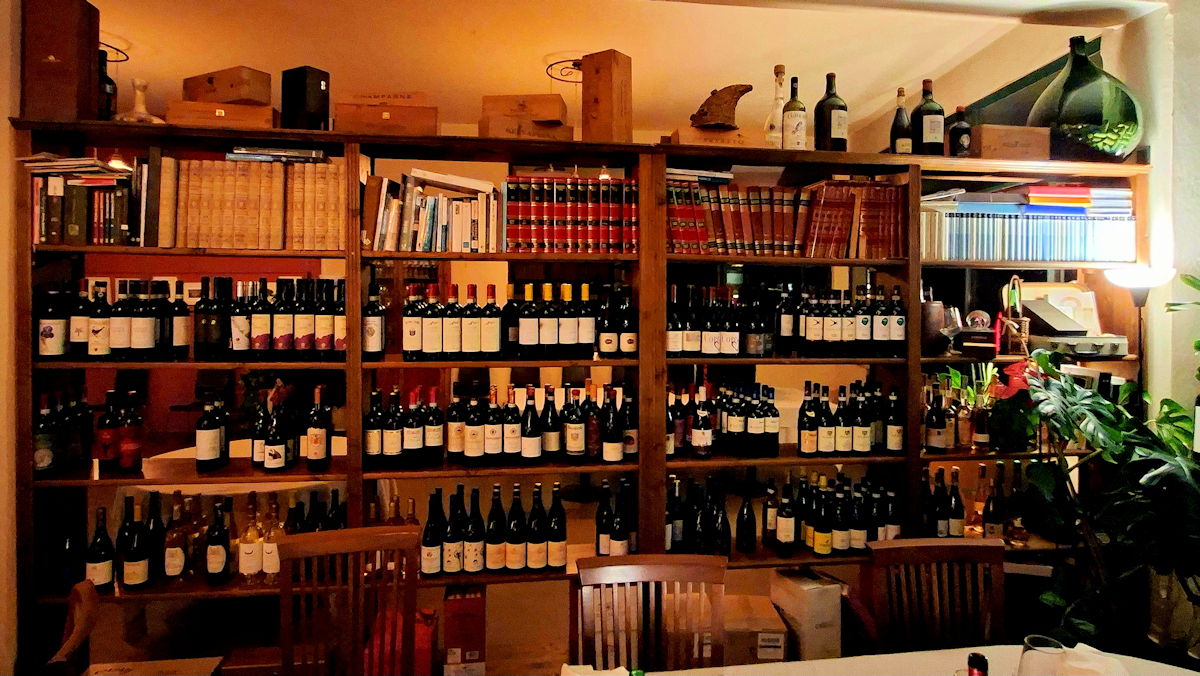 A shelf with books and bottles of wine