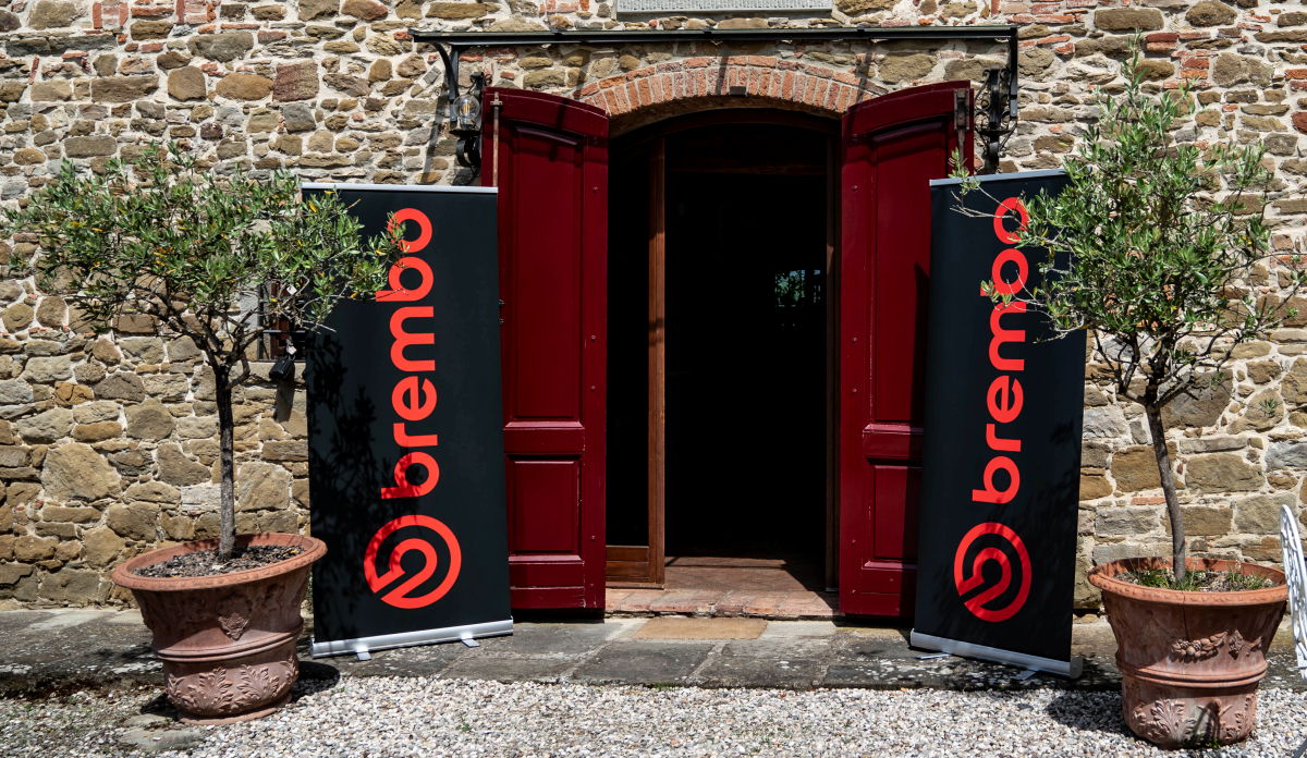 A front door, two potted trees, and two Brembo banners