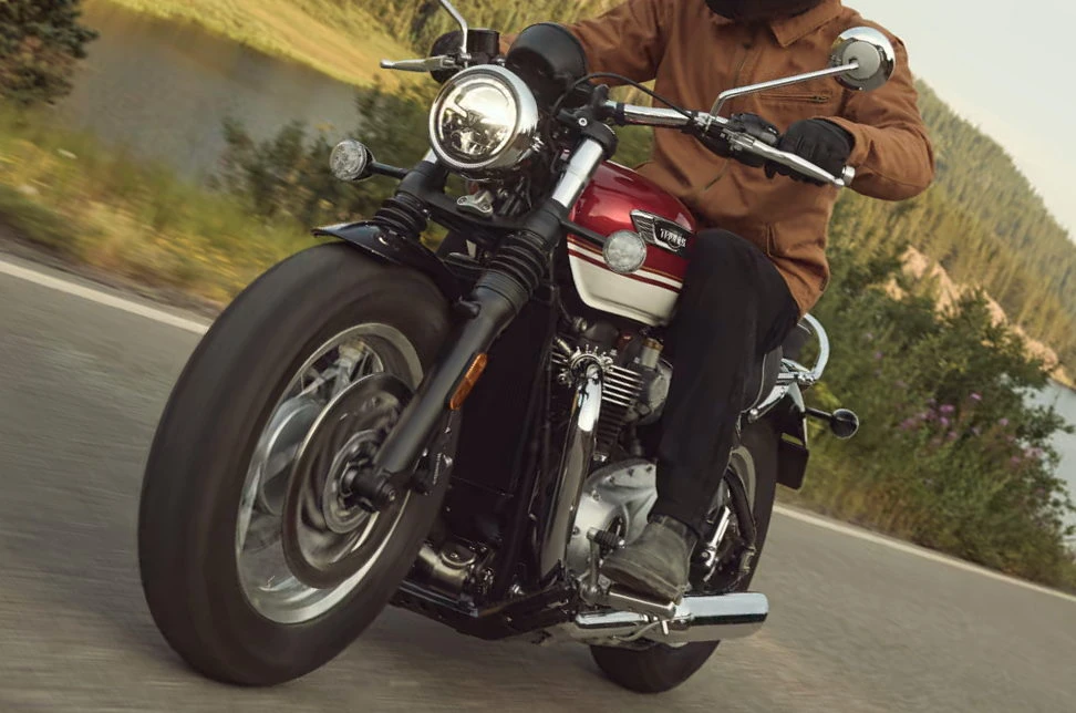 Une Triumph 1200 Speedmaster 2026 roulant devant un lac de montagne