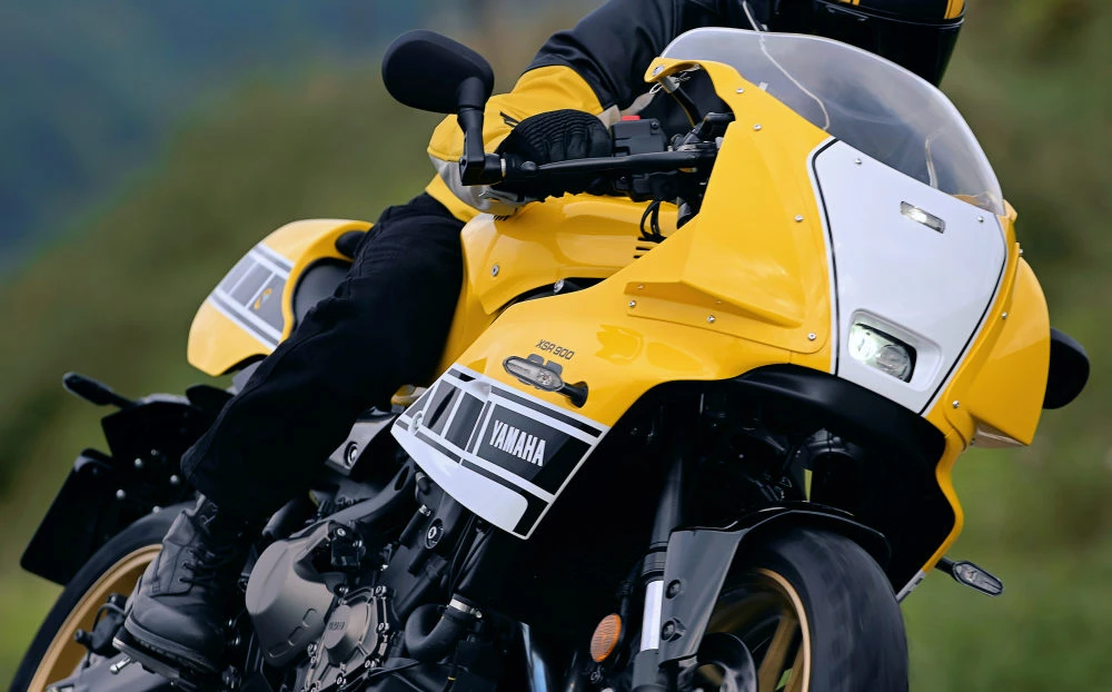 Une Yamaha XSR 900 GP avec le coloris jaune Legend Yellow roulant sur une route