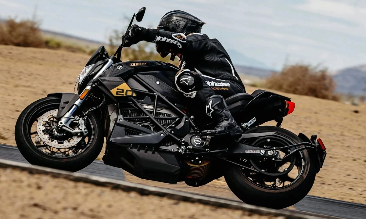 Une moto Zero SR/F 20th Anniversary sur circuit et un pilote avec un casque noir.
